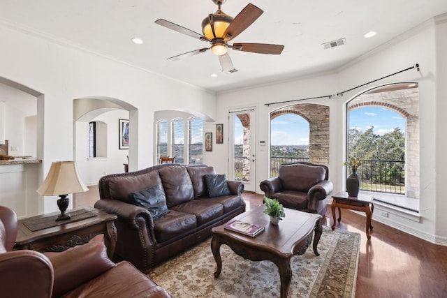 living area featuring a wealth of natural light, visible vents, and crown molding