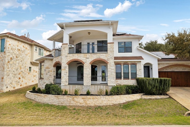 view of front of home with a front lawn, stucco siding, a balcony, and roof mounted solar panels