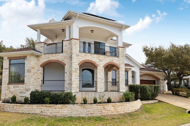 view of front of property with a balcony, concrete driveway, and stucco siding