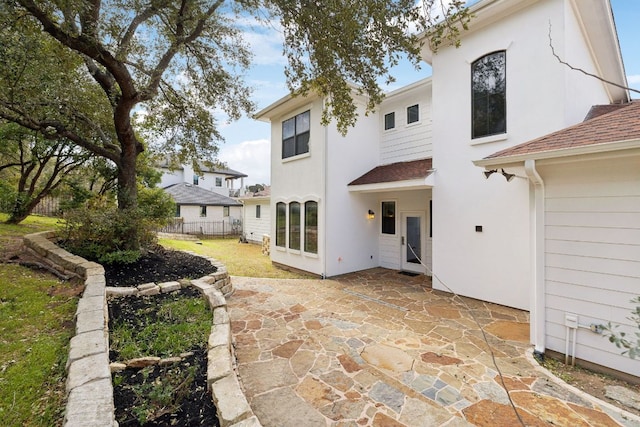 back of house featuring a patio area, a shingled roof, fence, and stucco siding