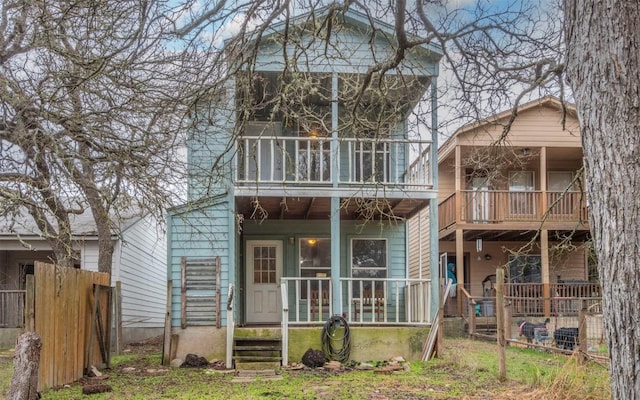 rear view of property with a balcony, fence, and covered porch