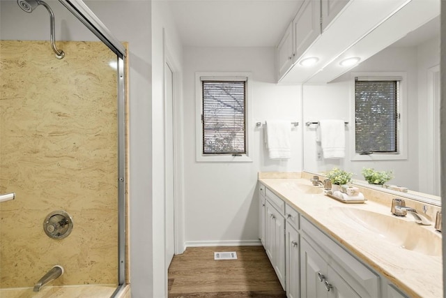 bathroom with double vanity, visible vents, a sink, wood finished floors, and baseboards