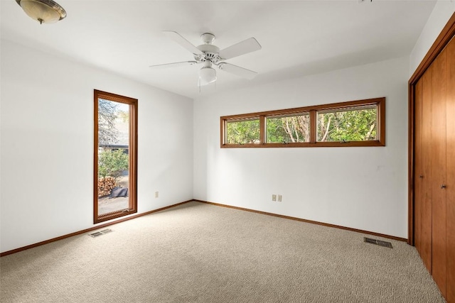 unfurnished room featuring a wealth of natural light, visible vents, and carpet flooring