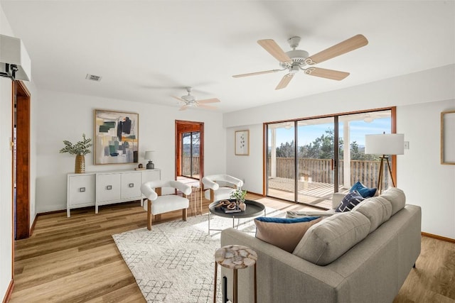 living area featuring light wood-style floors, baseboards, visible vents, and ceiling fan