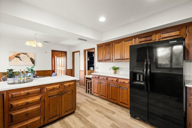 kitchen featuring light countertops, black fridge with ice dispenser, visible vents, and brown cabinets