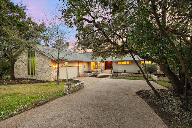 mid-century modern home with driveway, stone siding, and an attached garage