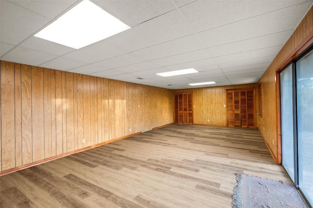 unfurnished room featuring a paneled ceiling, wood walls, and wood finished floors