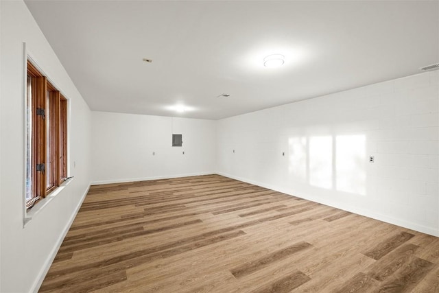 empty room featuring baseboards, electric panel, visible vents, and wood finished floors