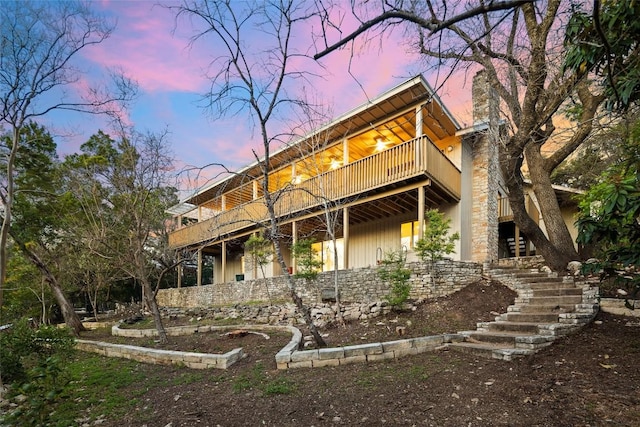 back of property featuring stone siding and stairway