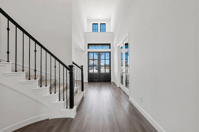 foyer with wood finished floors, french doors, a wealth of natural light, and baseboards