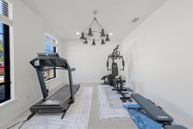 exercise room featuring visible vents, an inviting chandelier, carpet floors, and baseboards