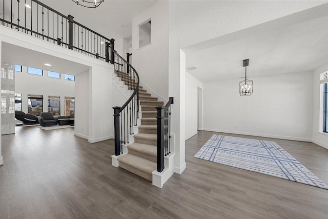 foyer entrance with an inviting chandelier, wood finished floors, baseboards, and a high ceiling