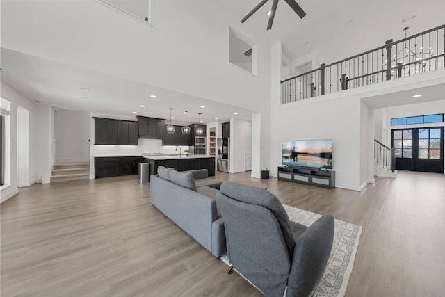 living area featuring baseboards, stairs, light wood finished floors, and a towering ceiling