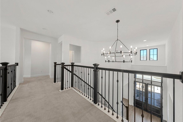 hallway featuring an upstairs landing, carpet flooring, baseboards, visible vents, and a notable chandelier