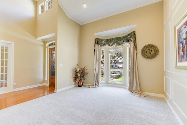 unfurnished room featuring ornamental molding, carpet flooring, and a high ceiling