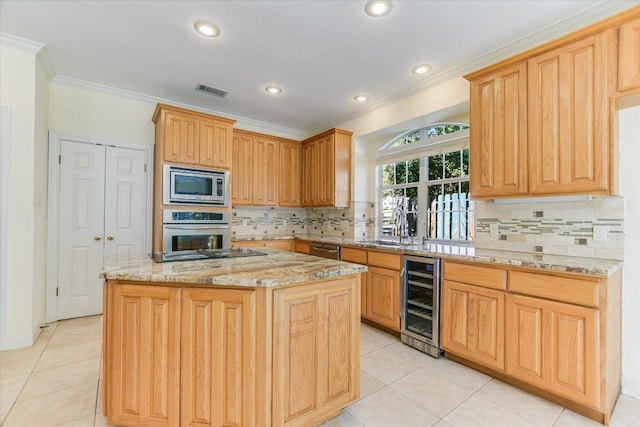 kitchen with beverage cooler, a kitchen island, appliances with stainless steel finishes, ornamental molding, and light tile patterned flooring