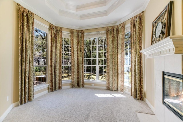 interior space featuring baseboards, a raised ceiling, a fireplace with flush hearth, carpet, and crown molding