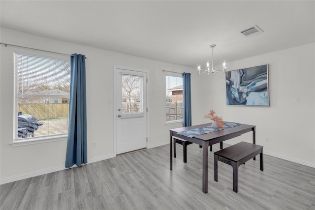 dining space with a chandelier, visible vents, baseboards, and wood finished floors