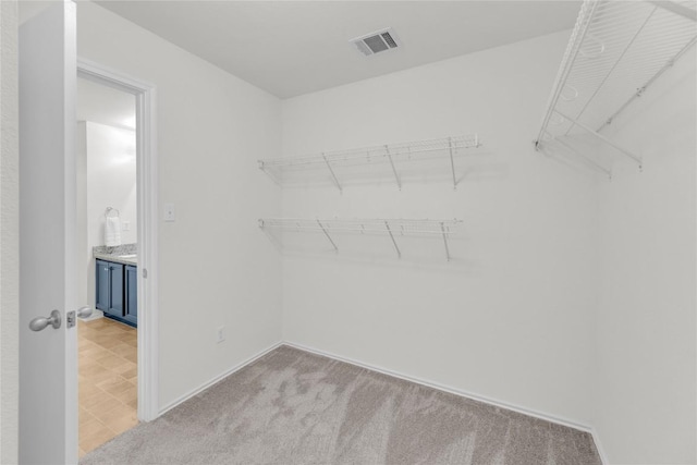 walk in closet featuring light carpet and visible vents