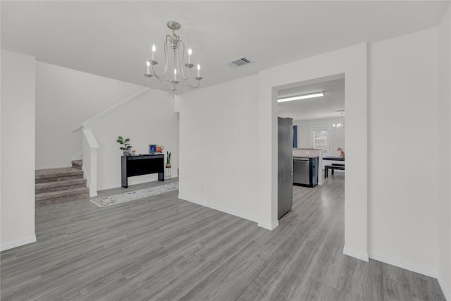 interior space featuring an inviting chandelier, light wood-style flooring, stairs, and visible vents