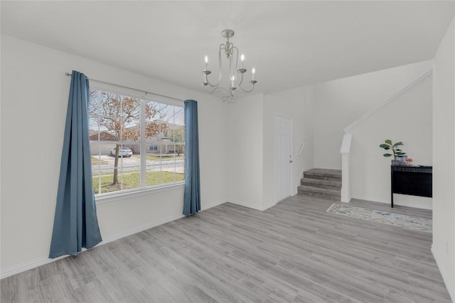 unfurnished dining area with an inviting chandelier, baseboards, stairway, and wood finished floors