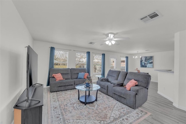 living area with a wealth of natural light, visible vents, and wood finished floors