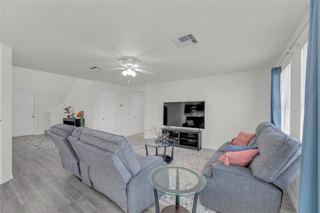 living area featuring light wood-type flooring, visible vents, and ceiling fan