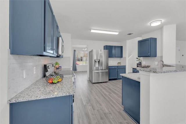 kitchen featuring blue cabinets, a peninsula, visible vents, appliances with stainless steel finishes, and backsplash