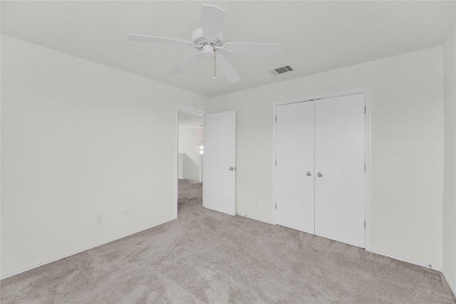 unfurnished bedroom with a closet, visible vents, ceiling fan, and carpet flooring