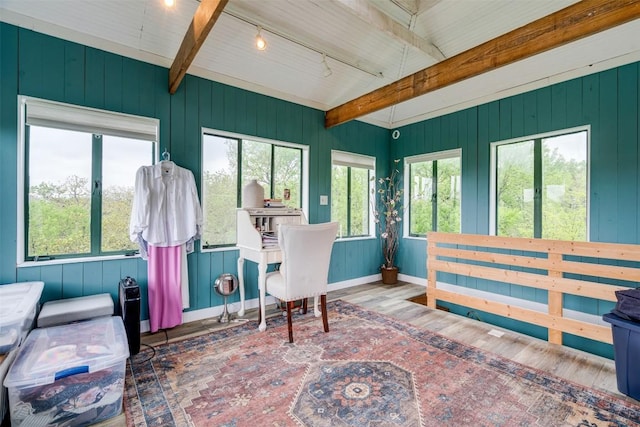 sunroom / solarium with rail lighting, beam ceiling, and a healthy amount of sunlight