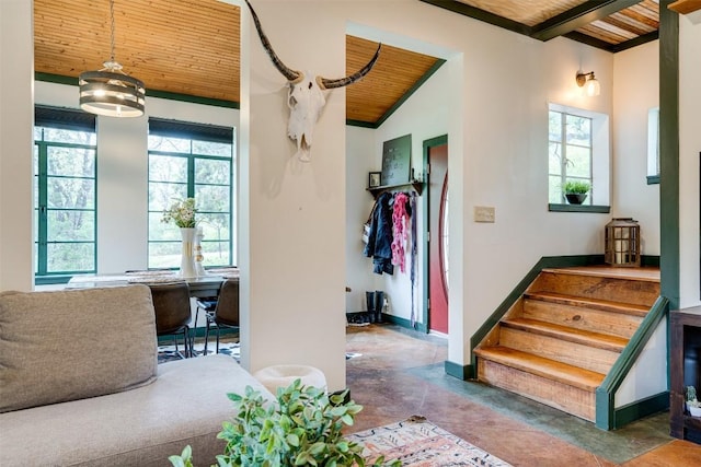 interior space featuring wooden ceiling, concrete floors, lofted ceiling with beams, and baseboards