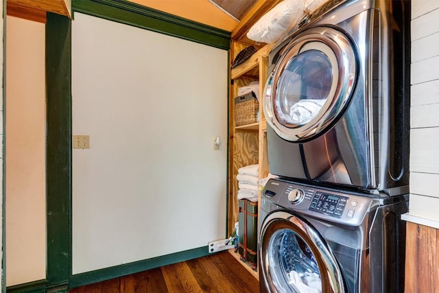 laundry area featuring laundry area, baseboards, dark wood-type flooring, and stacked washer / drying machine