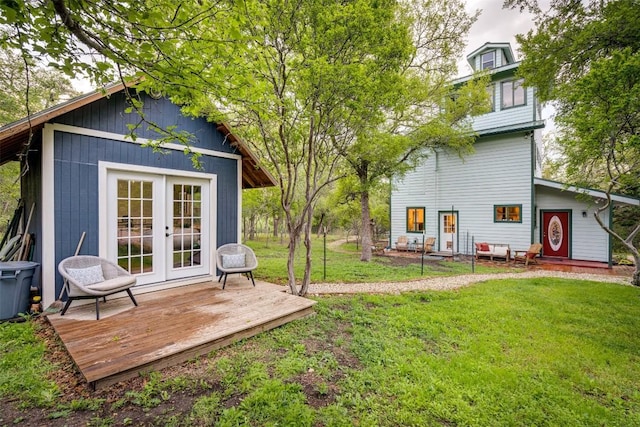 rear view of property with a deck, french doors, and a lawn