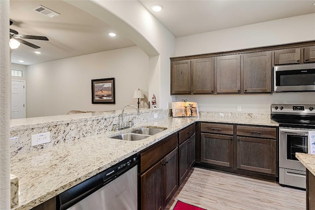 kitchen featuring light wood finished floors, visible vents, stainless steel appliances, dark brown cabinets, and a sink