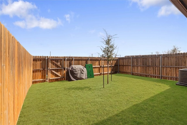 view of yard with central air condition unit, a fenced backyard, and a gate