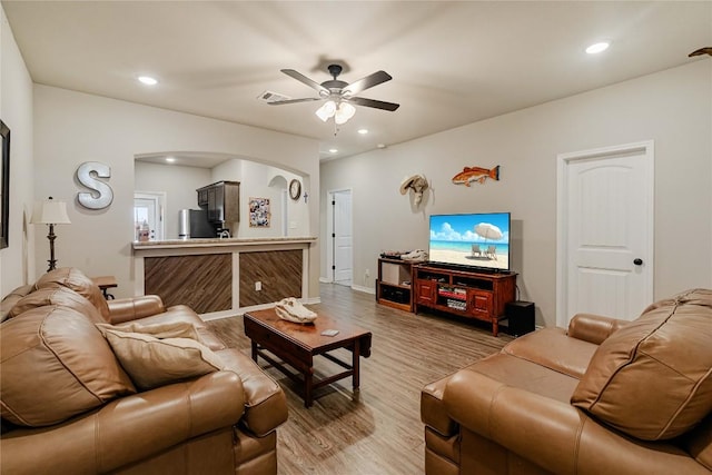 living room with light wood-style floors, arched walkways, a ceiling fan, and recessed lighting