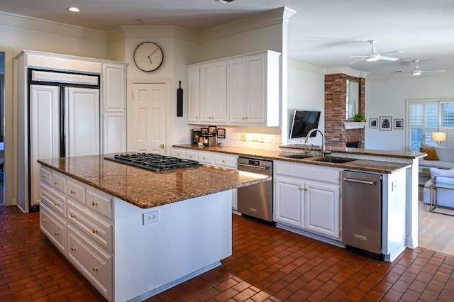 kitchen featuring gas stovetop, stainless steel dishwasher, open floor plan, white cabinets, and a sink