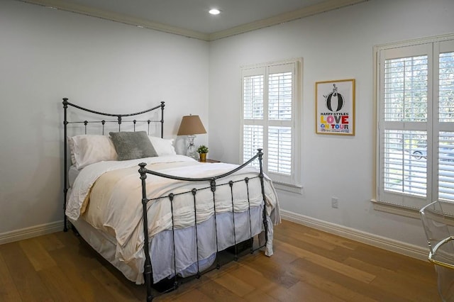 bedroom featuring multiple windows, baseboards, and wood finished floors