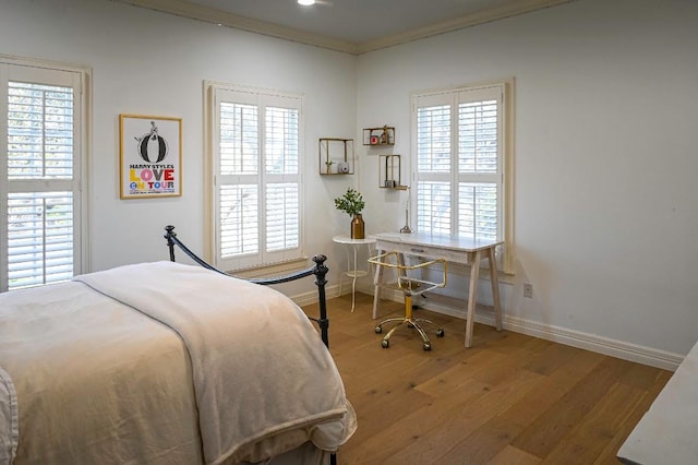 bedroom with multiple windows, baseboards, and wood finished floors