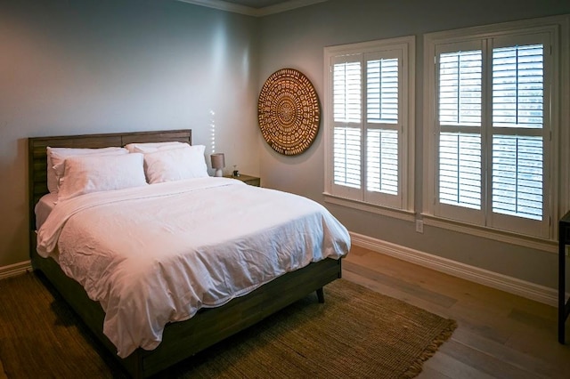 bedroom with multiple windows, baseboards, and wood finished floors