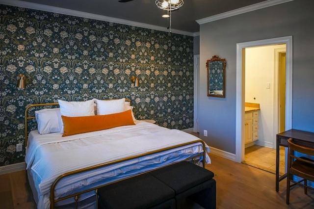 bedroom featuring wallpapered walls, baseboards, ensuite bath, ornamental molding, and wood finished floors