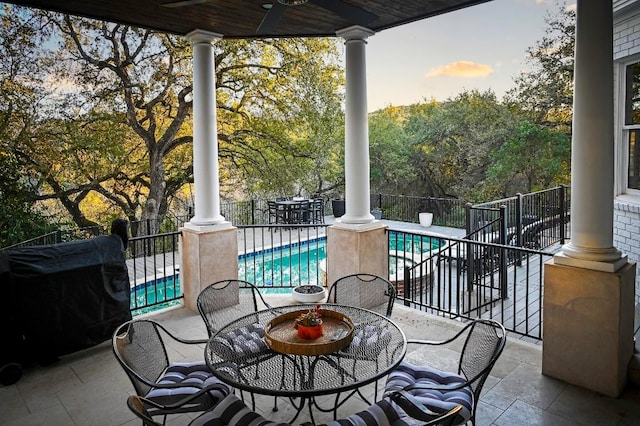 patio terrace at dusk featuring fence, a fenced in pool, and outdoor dining space