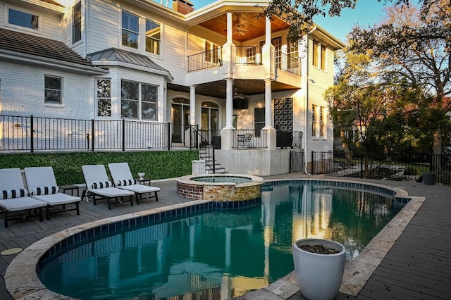 view of swimming pool featuring a pool with connected hot tub, fence, a ceiling fan, and a patio