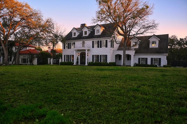 colonial-style house featuring a chimney and a front lawn