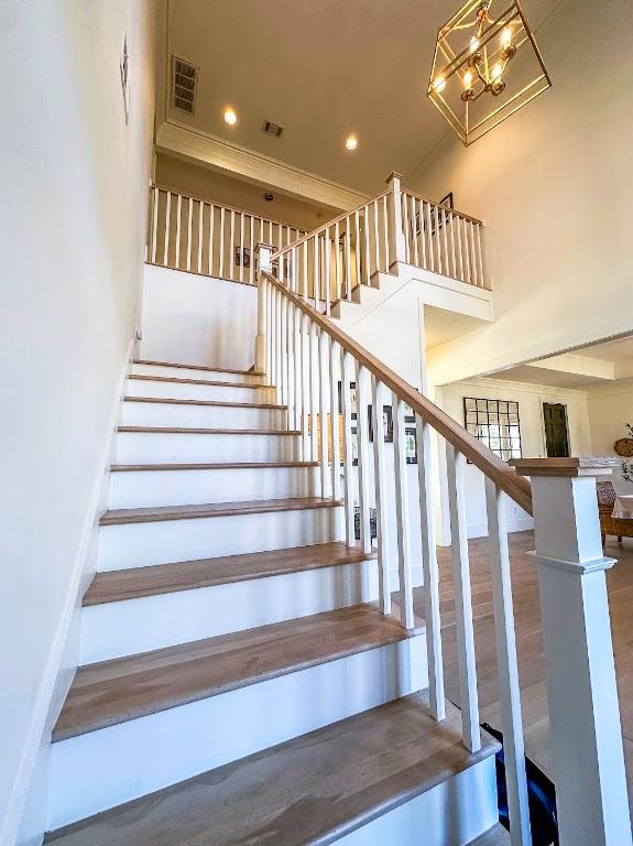 stairs featuring visible vents, wood finished floors, a towering ceiling, and recessed lighting