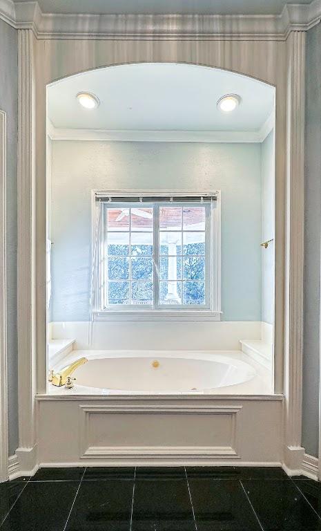 bathroom with ornamental molding and a bath