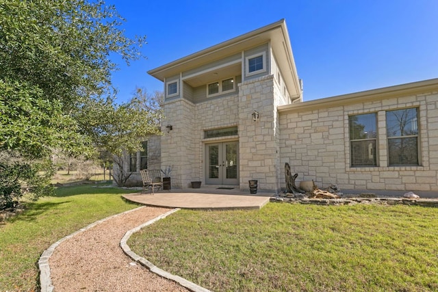 rear view of property with stone siding, french doors, a lawn, and a patio area