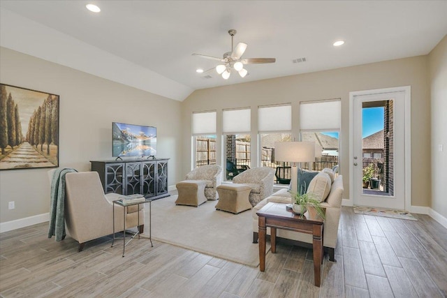 interior space with ceiling fan, visible vents, baseboards, vaulted ceiling, and light wood-type flooring