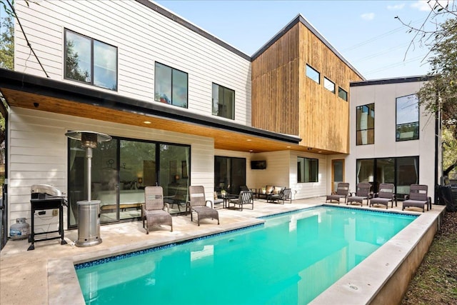 back of property featuring a patio area and an outdoor pool