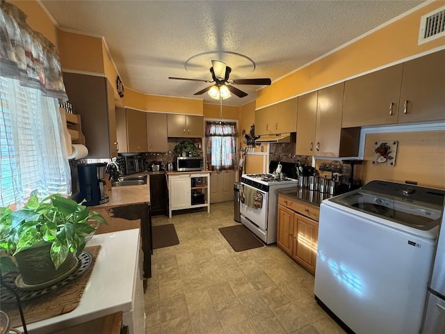 kitchen featuring tasteful backsplash, visible vents, stainless steel microwave, white gas range, and under cabinet range hood